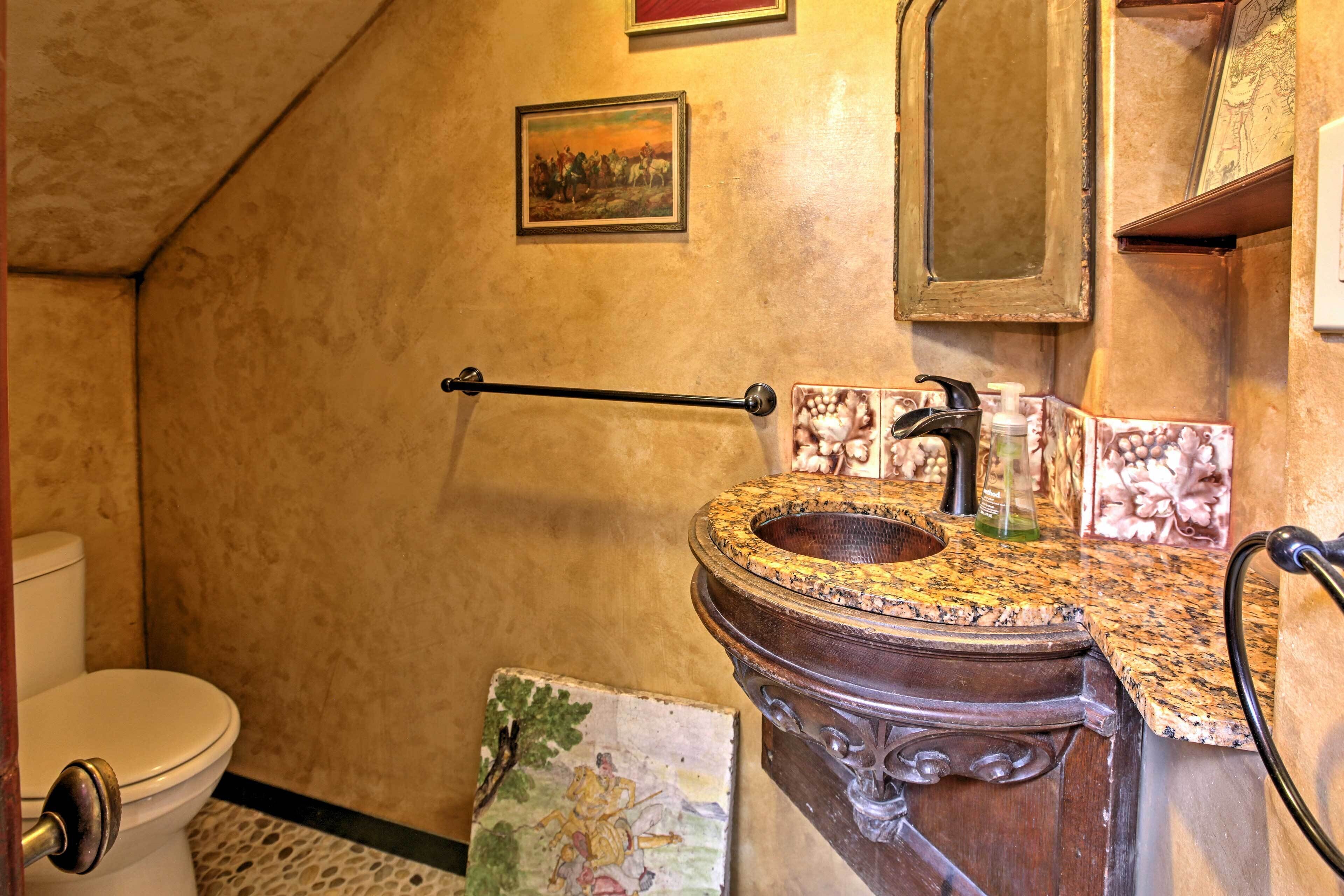 A bathroom with a marble sink, a towel rack, and a painting on the wall.