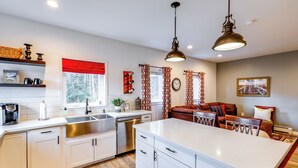 A modern kitchen with white cabinetry, a large island, stainless steel appliances, and a red patterned rug. - Convenient Fairbanks Guest Suite w/ Grill! (Fairbanks)