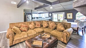 A spacious living room with a large sectional sofa, a leather ottoman, and a kitchen in the background. - Lakefront Family Home, Recently Renovated! (Trinidad)
