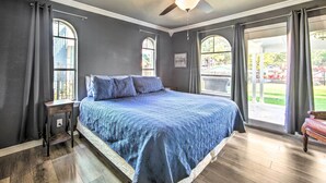 A bedroom with a large bed, a ceiling fan, and two windows with curtains. - Lakefront Family Home, Recently Renovated! (Trinidad)