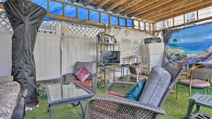 An outdoor patio with wicker furniture, a TV, and a large mural.