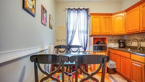 A kitchen with wooden cabinets, a dining table with chairs, and a window with curtains.