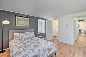 A bedroom with a bed, a bedside table, a lamp, a framed picture on the wall, and a window with blinds. - Sleek Albrightsville Home w/ Deck, Game Room (Albrightsville)