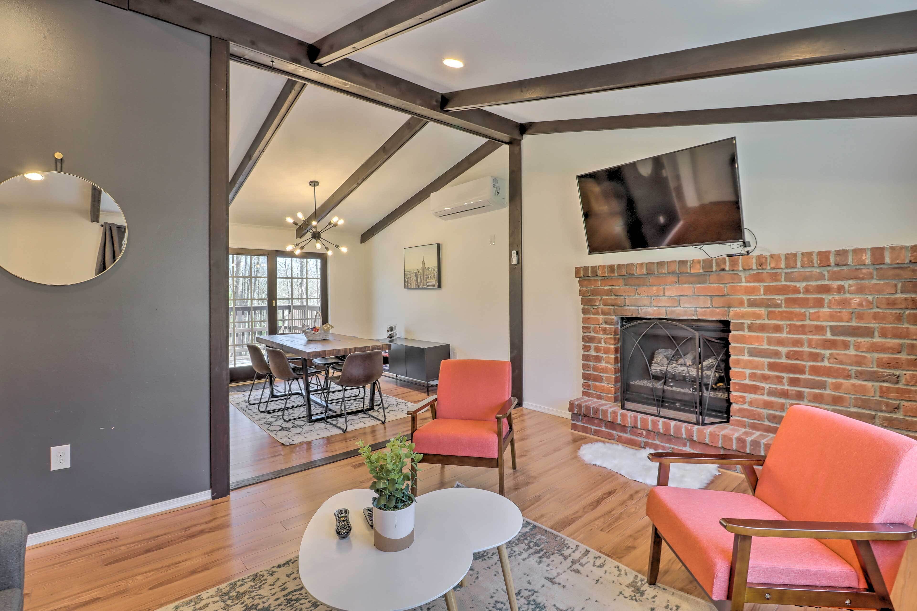 A modern living room with a fireplace, a dining area, and a large window.