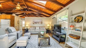 A spacious living room with a high ceiling, a fireplace, a television, and a bookshelf. - Breathtaking Newbury Cottage w/ Deck on Chalk Pond (Newbury)