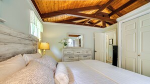 A bedroom with a wooden ceiling, a bed with patterned bedding, a dresser with drawers, and a mirror above the dresser. - Breathtaking Newbury Cottage w/ Deck on Chalk Pond (Newbury)