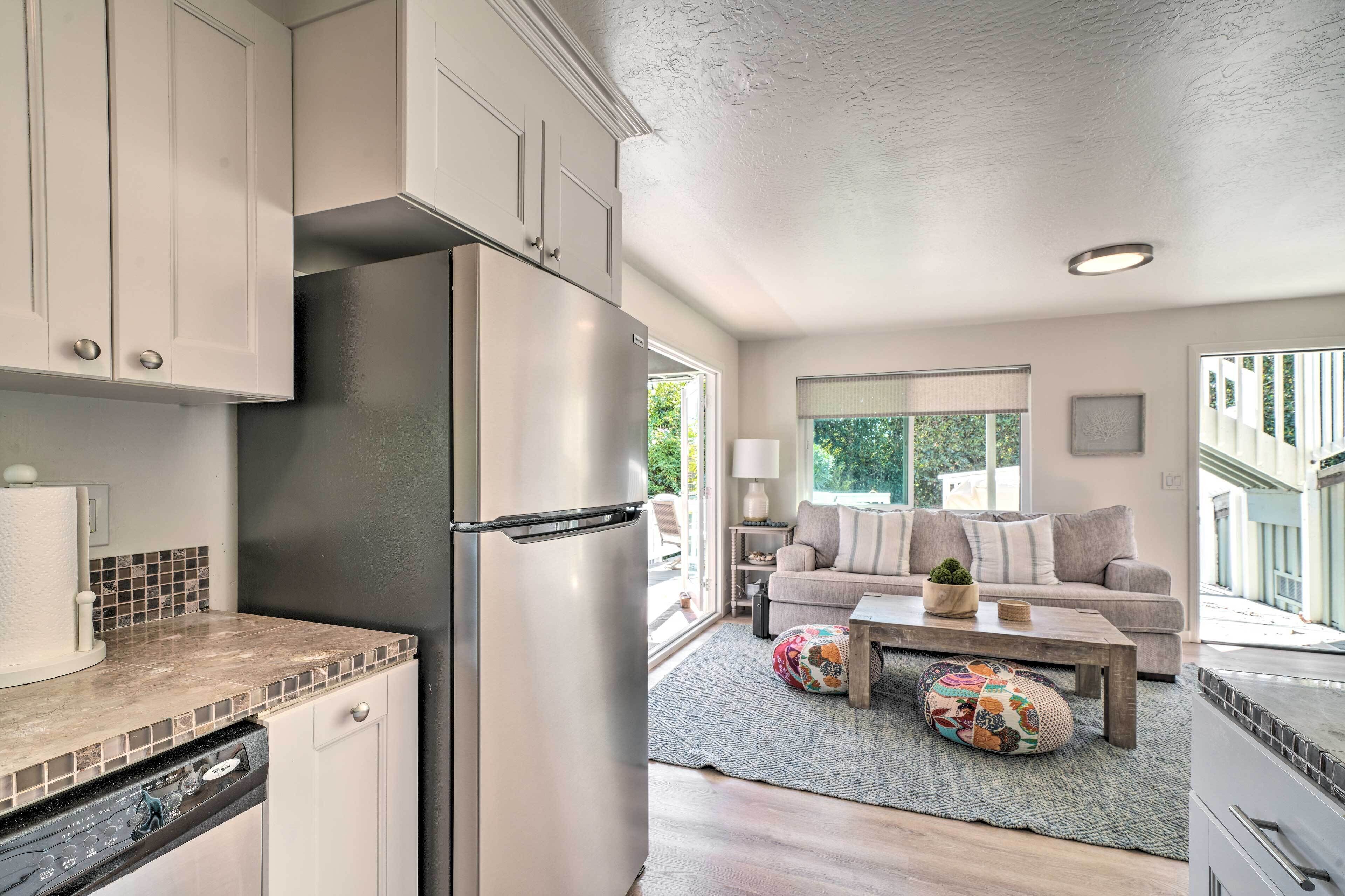 A modern kitchen with stainless steel appliances, a dishwasher, and a dining area with a sofa and coffee table.