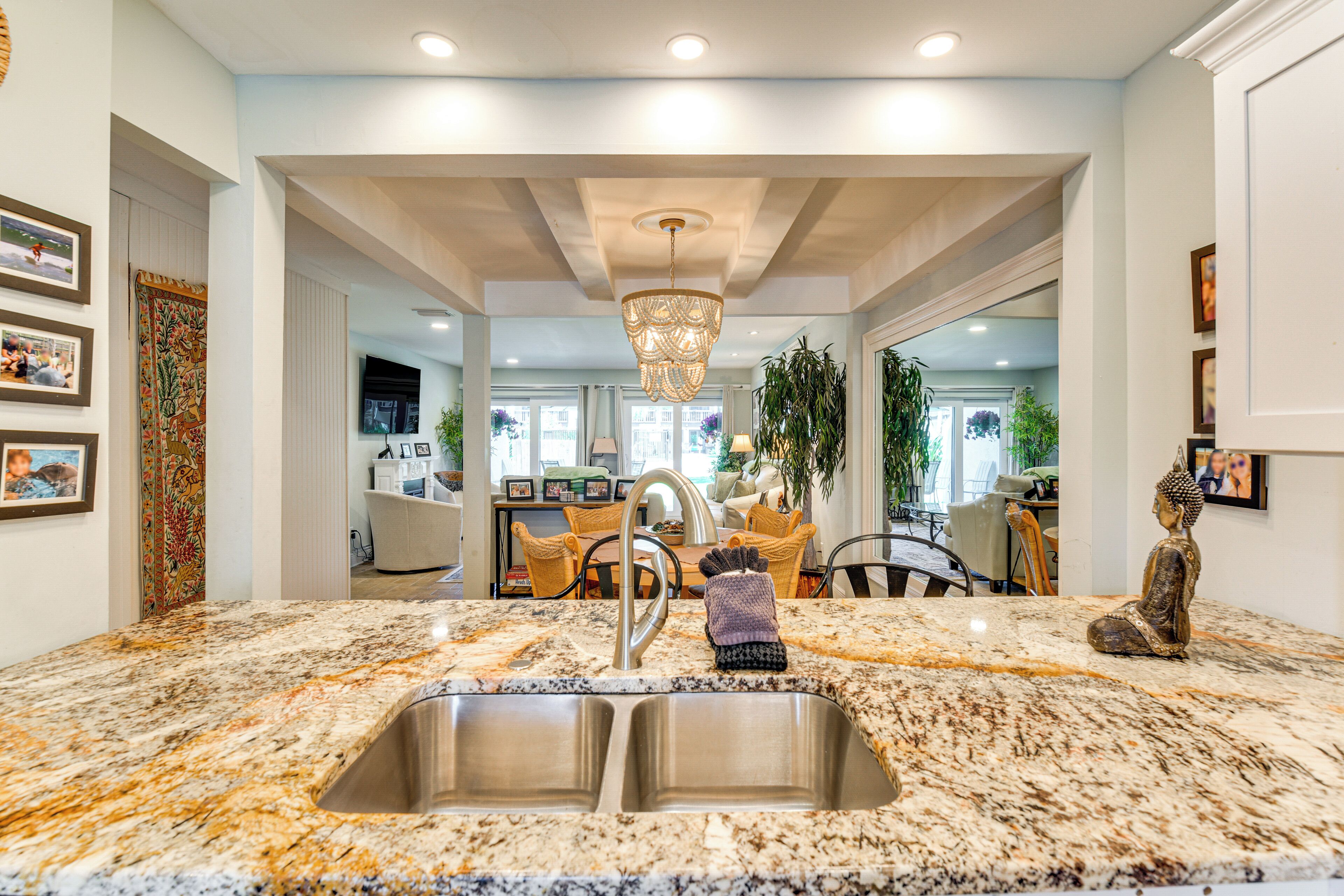 A kitchen with a granite countertop, stainless steel sink, and a hanging light fixture.