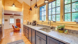 A kitchen with wooden walls, granite countertops, a sink, and pendant lights. - Private Island w/ 2 Cottages on Kezar Lake! (Lovell)