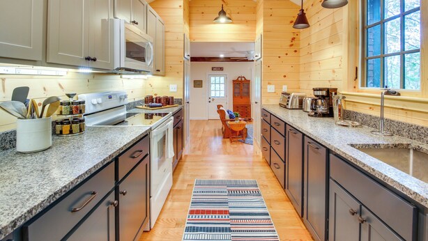 A kitchen with wooden walls, granite countertops, and a central island. - Private Island w/ 2 Cottages on Kezar Lake! (Lovell)