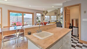 A modern kitchen with a large island, wooden dining table, and chairs.