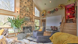 A spacious living room with a stone fireplace, large windows, and a cozy seating area.