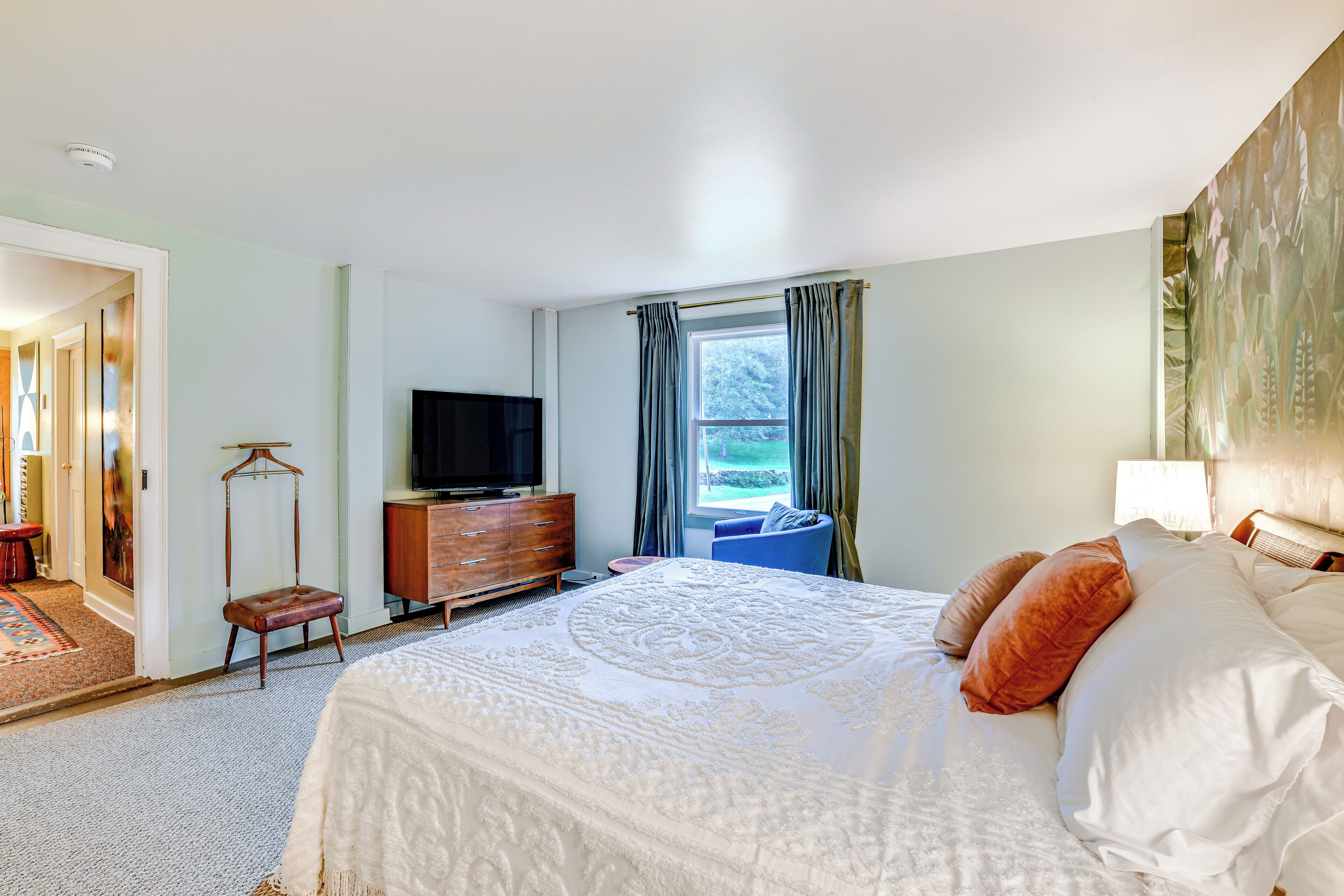 Habitación de hotel con una cama grande, cómoda, televisor y ventana con cortinas.