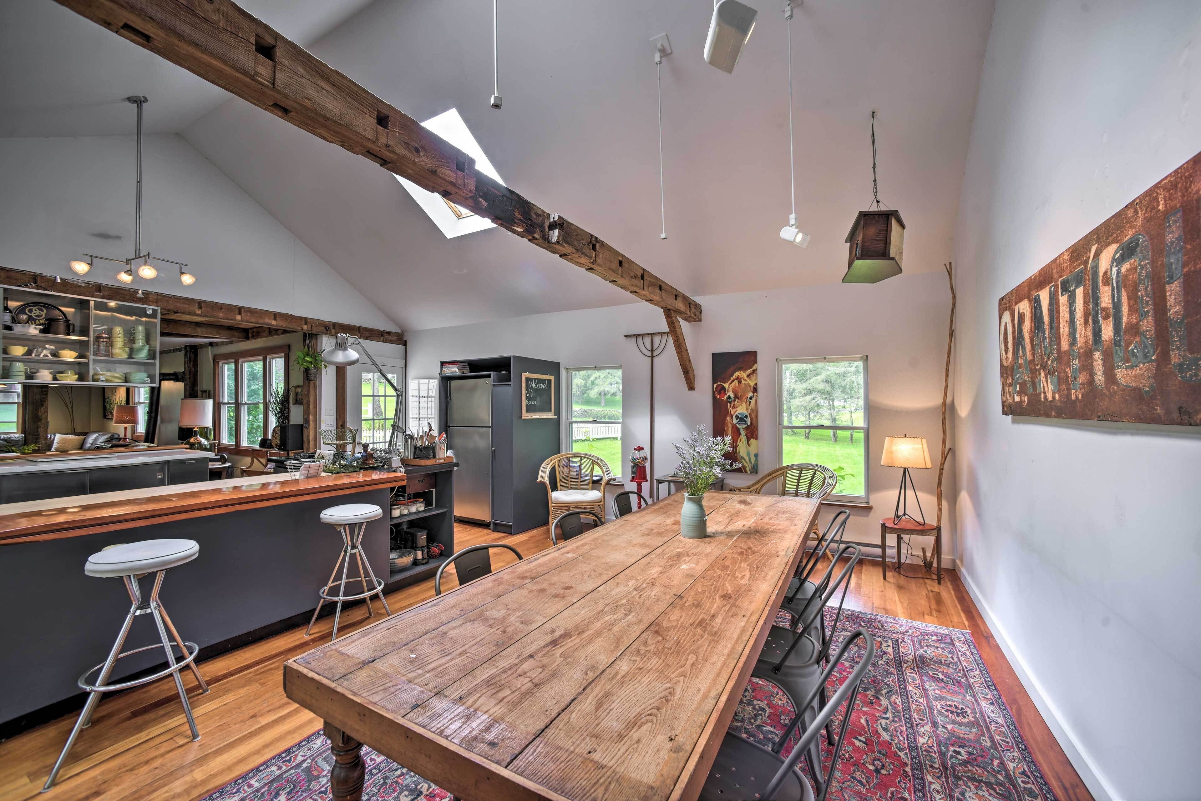A spacious kitchen with a wooden island, bar stools, and a large dining table.