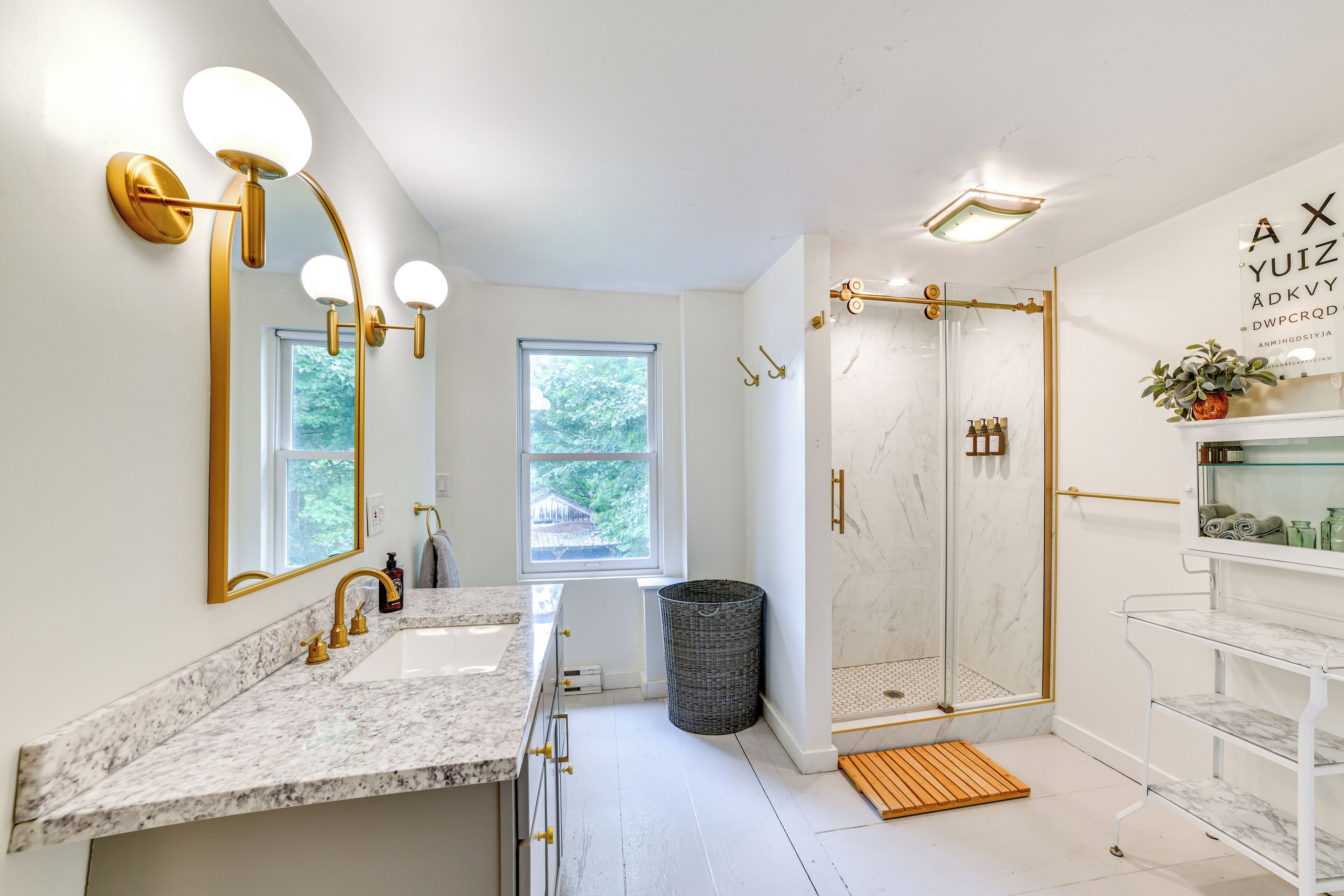 A modern bathroom with a large vanity, a walk-in shower, and a window providing natural light.