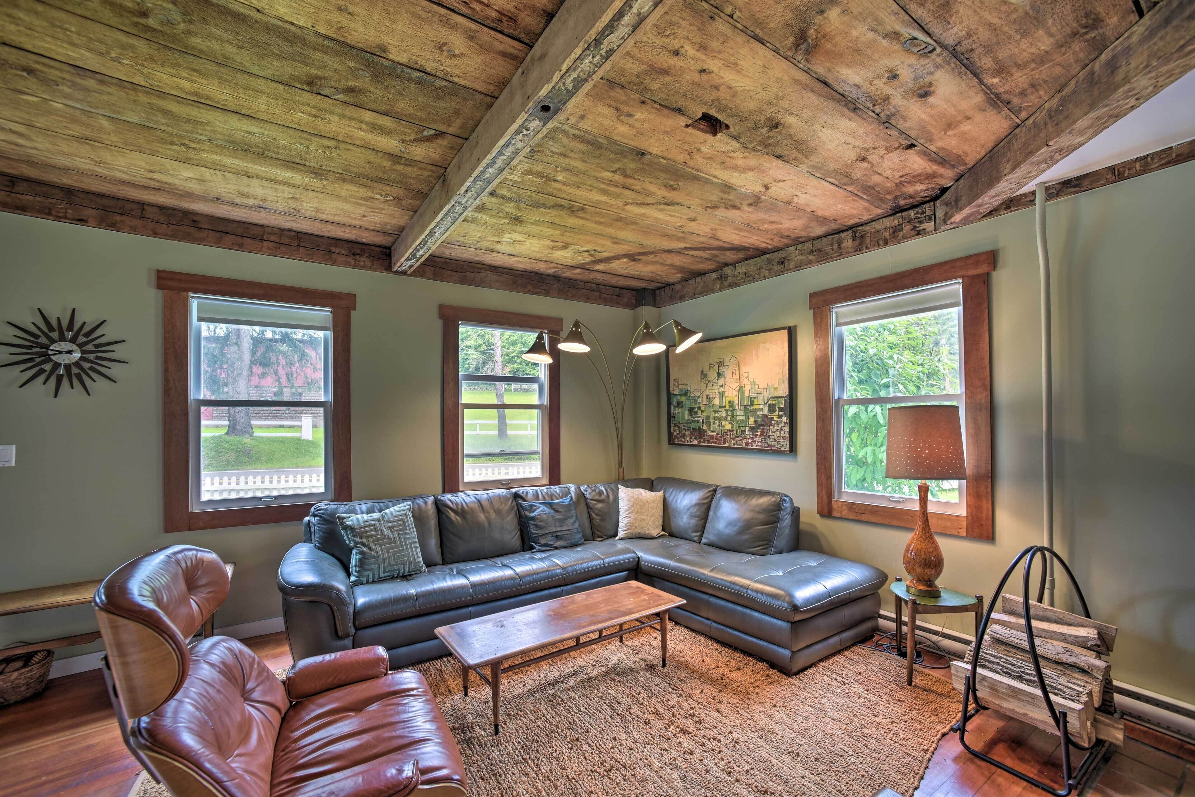 A spacious living room with a large sectional sofa, a wooden coffee table, and a rustic ceiling.