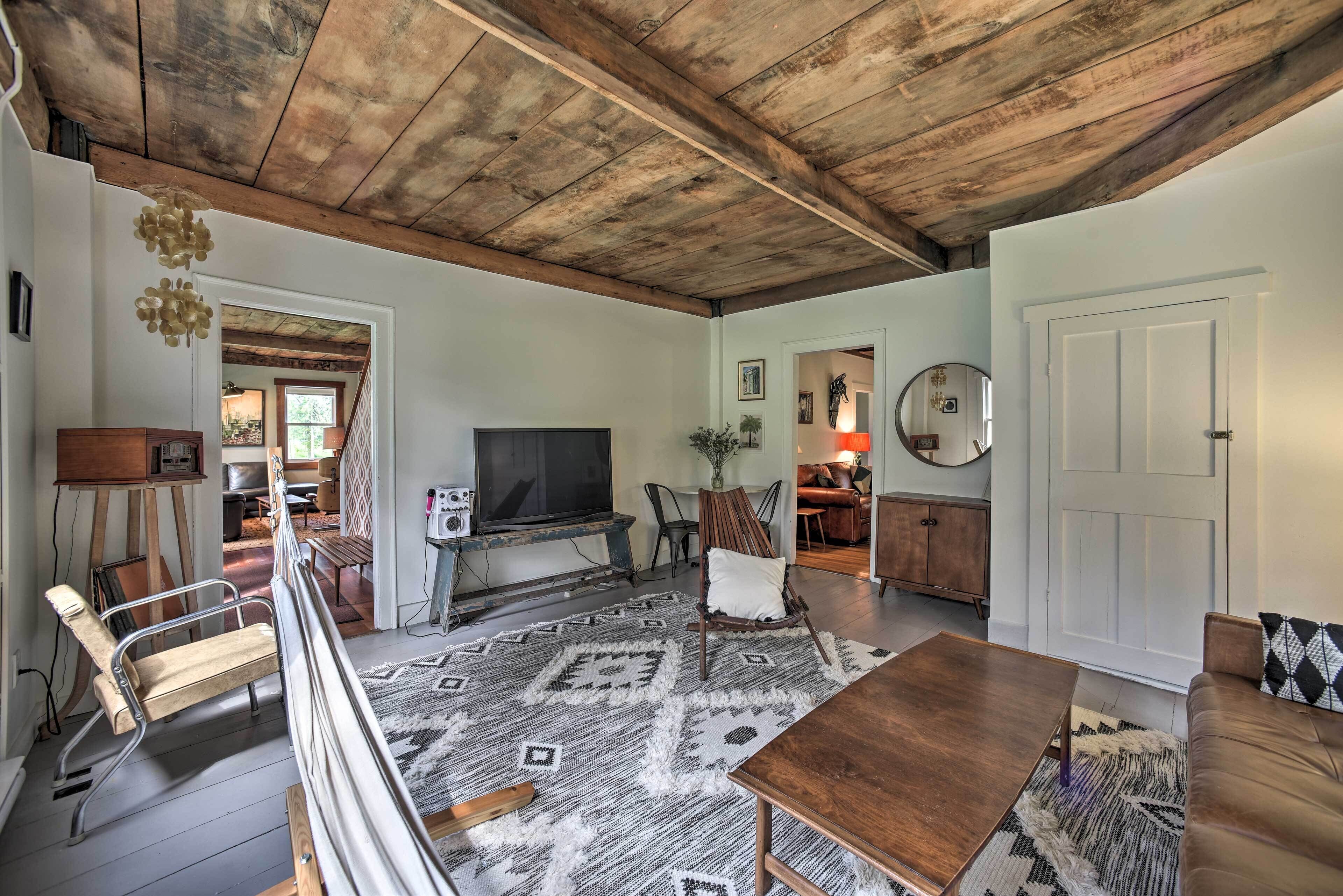 A spacious living room with a high wooden ceiling, a large TV, and a cozy seating area with a sofa and chairs.