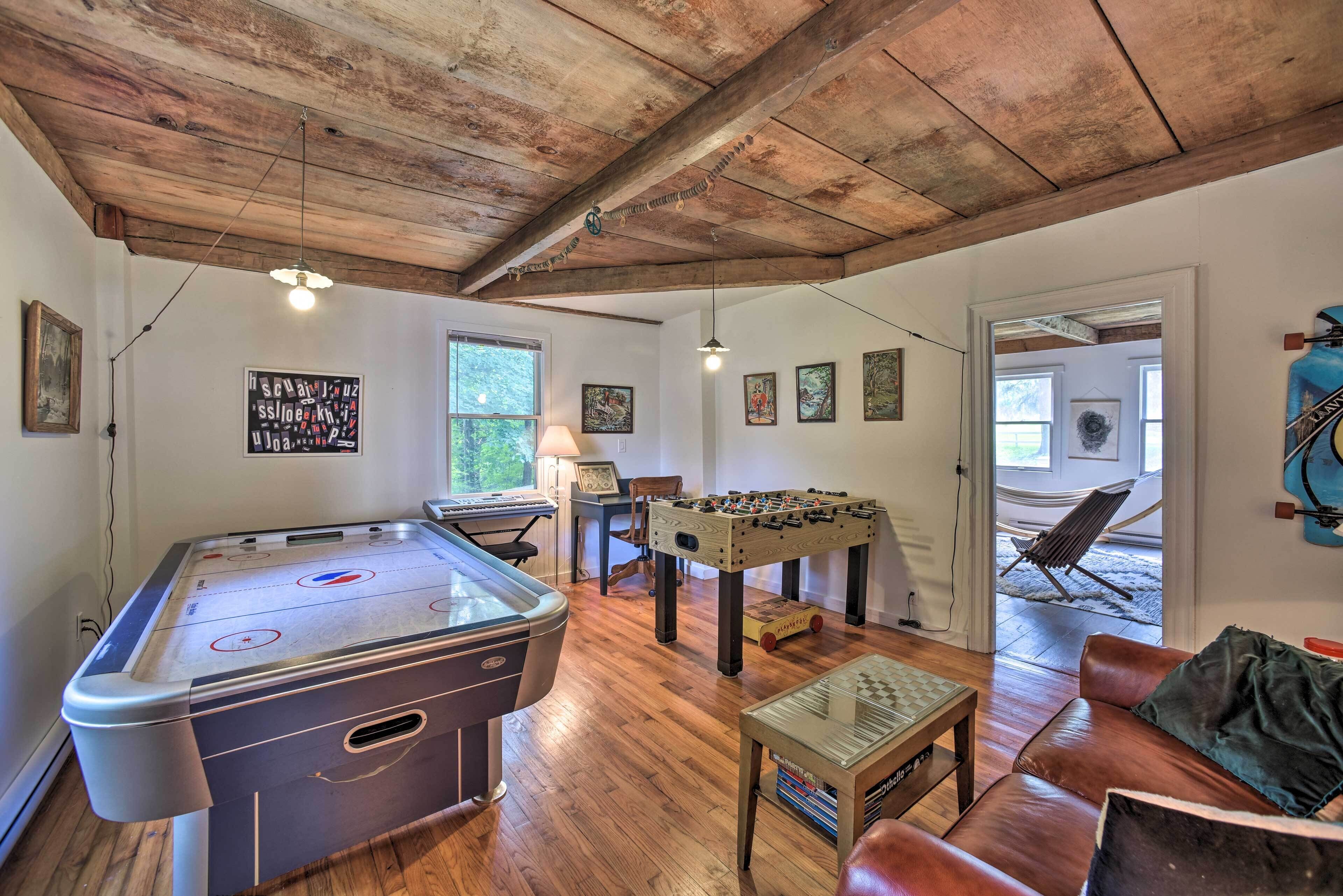 A cozy room with a foosball table, a pool table, and a foosball table in the corner.