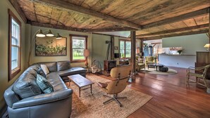 Ein geräumiges Wohnzimmer mit einem großen Ecksofa, einem modernen Sessel und einer Holzbalkendecke.