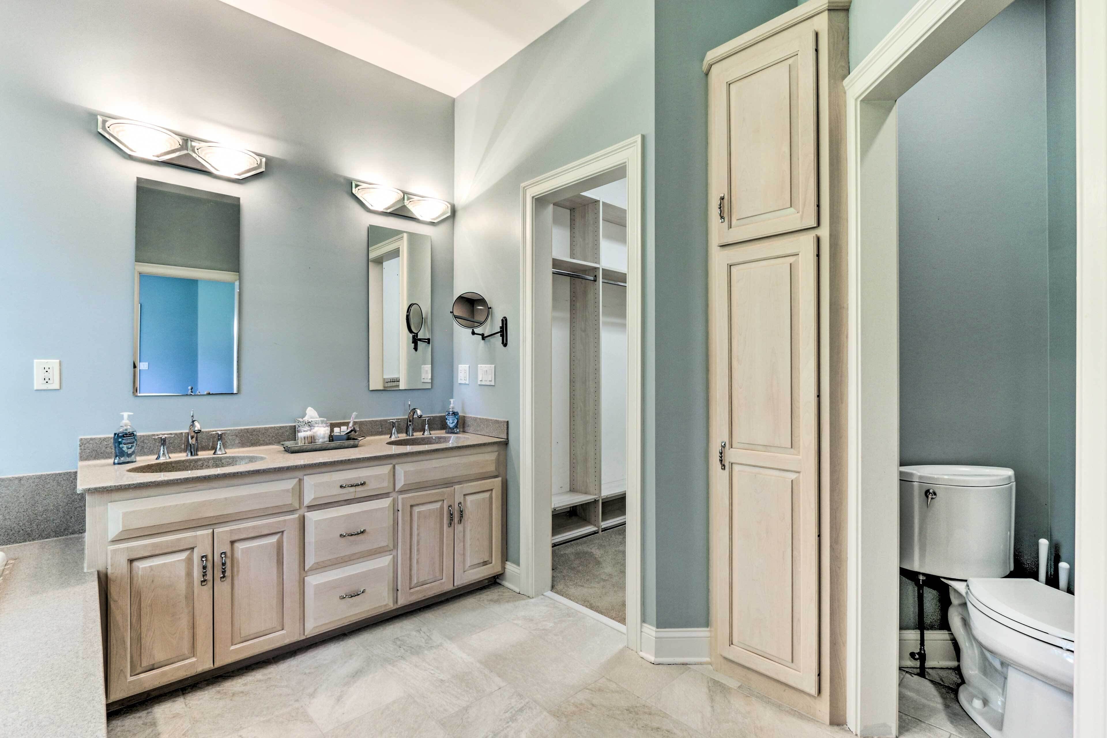 A bathroom with a large vanity, a toilet, and a walk-in closet.