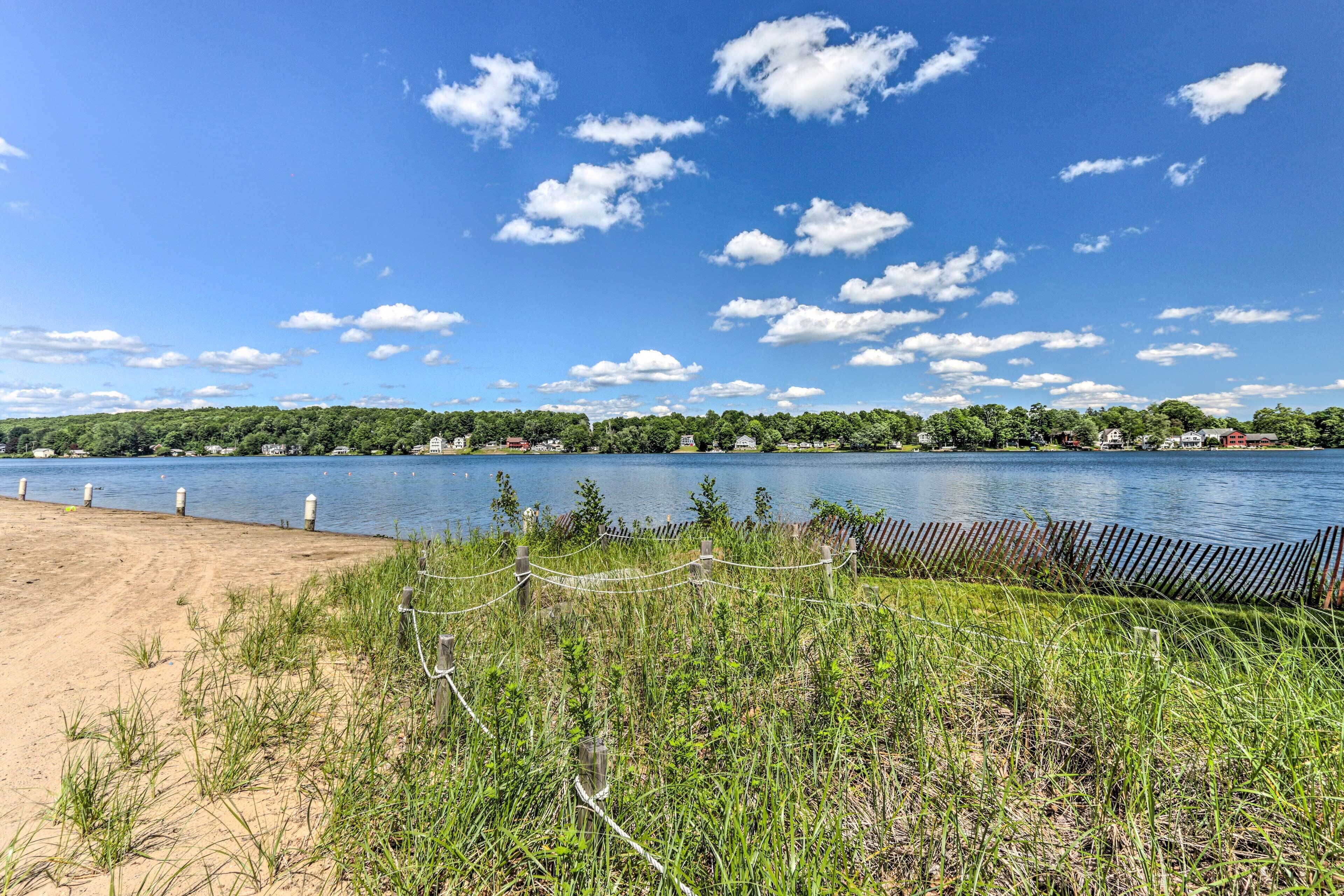 Une plage bordée d’une clôture en bois, d’où l’on a une vue dégagée sur un lac.