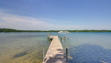 Un muelle de madera que se adentra en un lago tranquilo, con un pabellón al final.