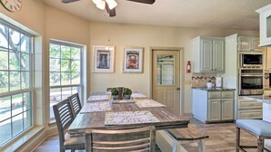 Une cuisine avec une table en bois, des chaises, des placards et un ventilateur de plafond.