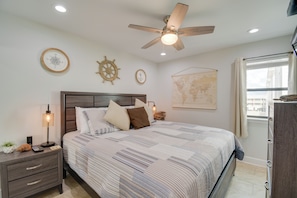 Quarto com cama, mesa de cabeceira, luminária e ventilador de teto.