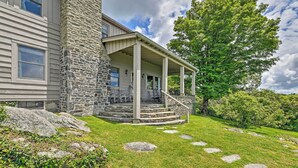 A stone and wood house with a covered porch, steps leading to the entrance, and a grassy yard with stepping stones. - Amazing Historic Home w/ Stunning Mountain Views! (Blowing Rock)
