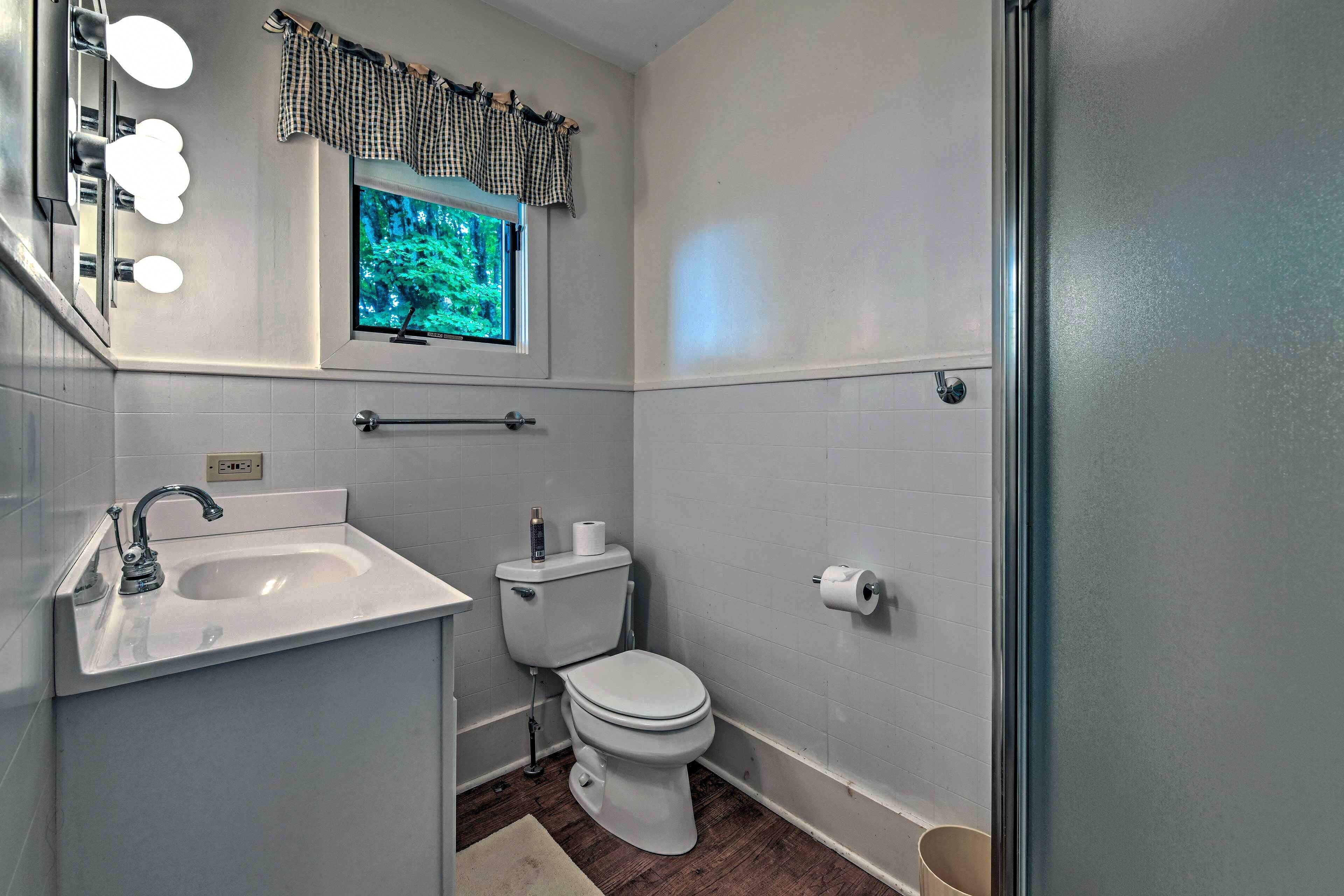 A bathroom with a sink, toilet, and window.