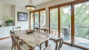 A dining area with a wooden table and chairs, a chandelier, a framed picture on the wall, and a view of a balcony with a railing. - Expansive Edwards Condo on Main Street w/ Views! (Edwards)