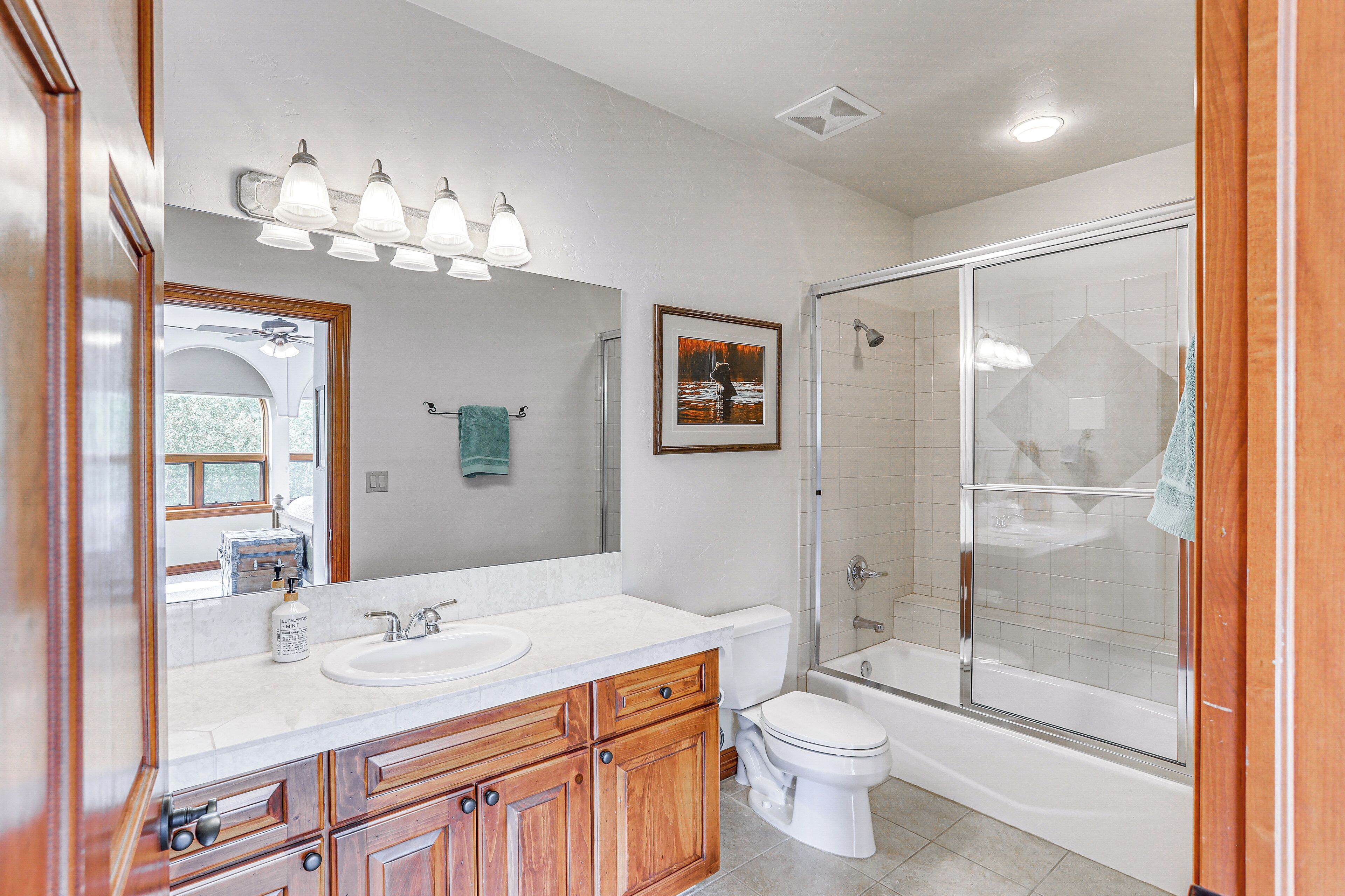 A modern bathroom with a large mirror, a sink, a toilet, and a shower area.