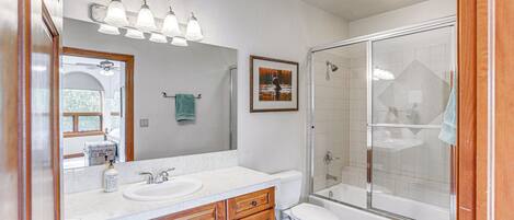 A modern bathroom with a large mirror, a sink, a toilet, and a shower area.