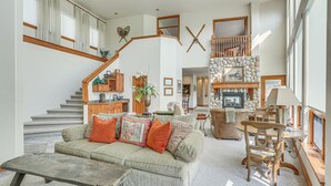 A spacious living area with a staircase, a stone fireplace, and a dining table with chairs. - Expansive Edwards Condo on Main Street w/ Views! (Edwards)