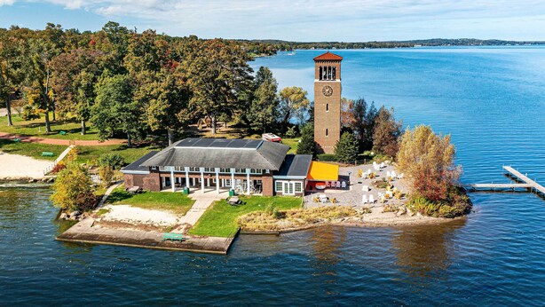 A lakeside building with a clock tower, surrounded by trees and a dock. - Bemus Point Vintage Suite w/ Soaking Tub & Kitchen (Bemus Point)