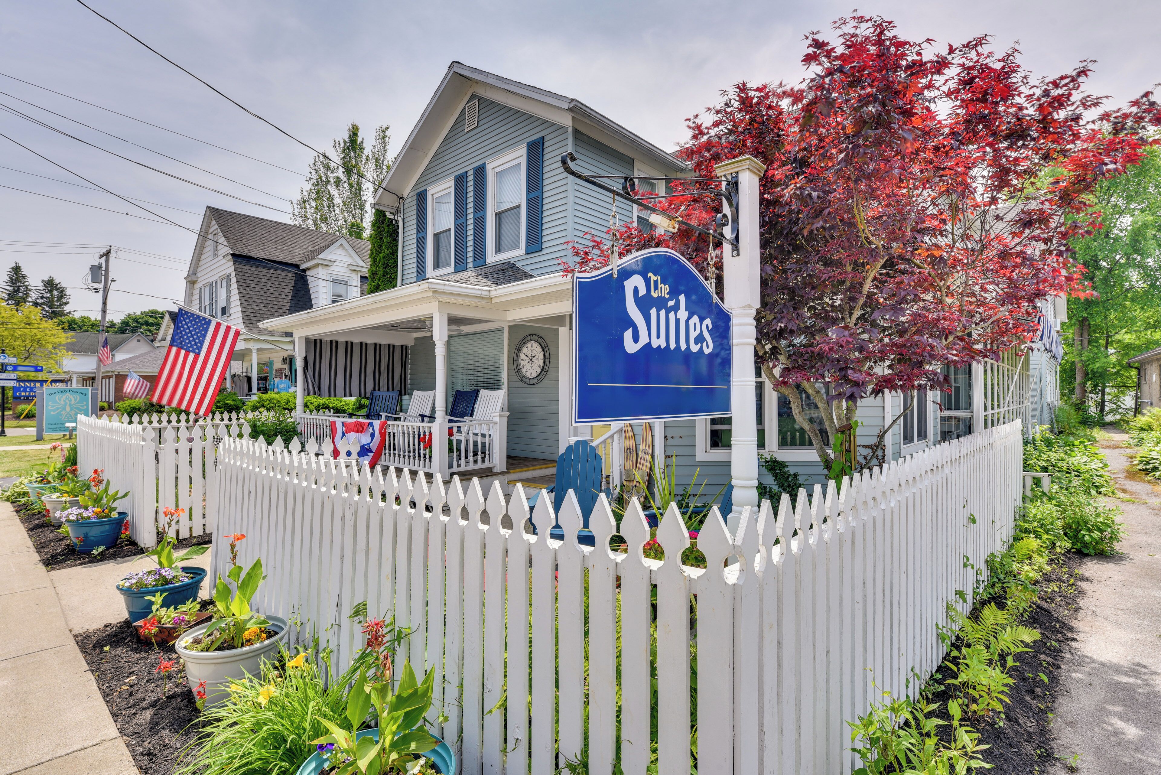 A hotel with a blue exterior, a white picket fence, and a sign that reads "The Suites."