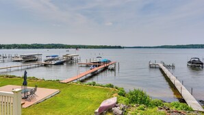 A lakeside dock with boats, a covered seating area, and a grassy deck. - Bemus Point Vintage Suite w/ Soaking Tub & Kitchen (Bemus Point)