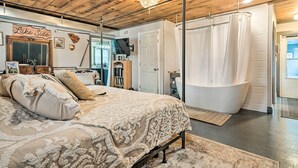 A bedroom with a large bed, a wooden ceiling, a chandelier, a bathtub, and a sign that reads "Lake Side". - Bemus Point Vintage Suite w/ Soaking Tub & Kitchen (Bemus Point)