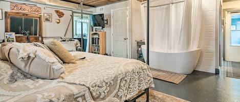 A bedroom with a large bed, a wooden ceiling, a chandelier, a bathtub, and a sign that reads "Lake Side".