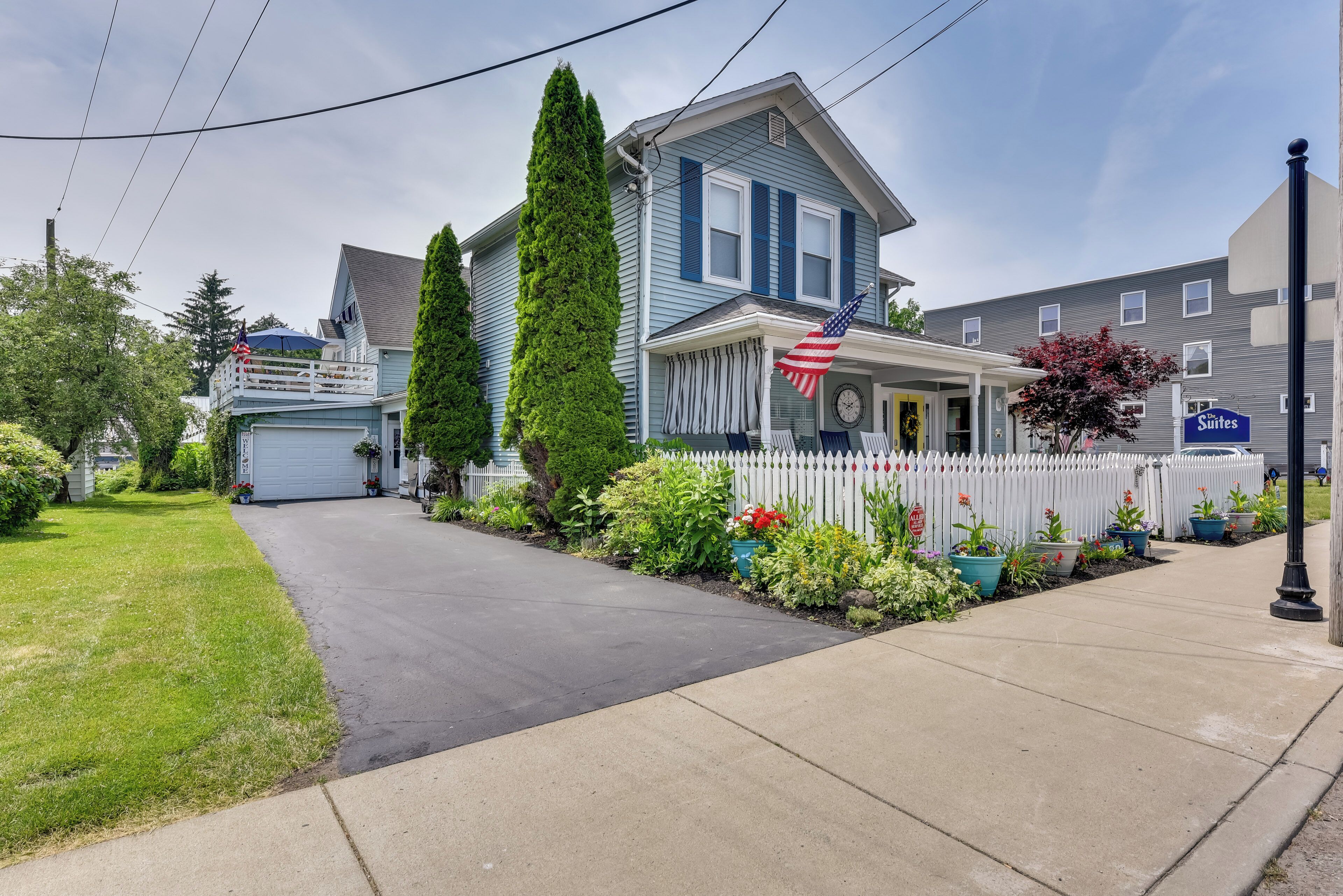 A two-story house with a front porch, a garage, and a white picket fence.