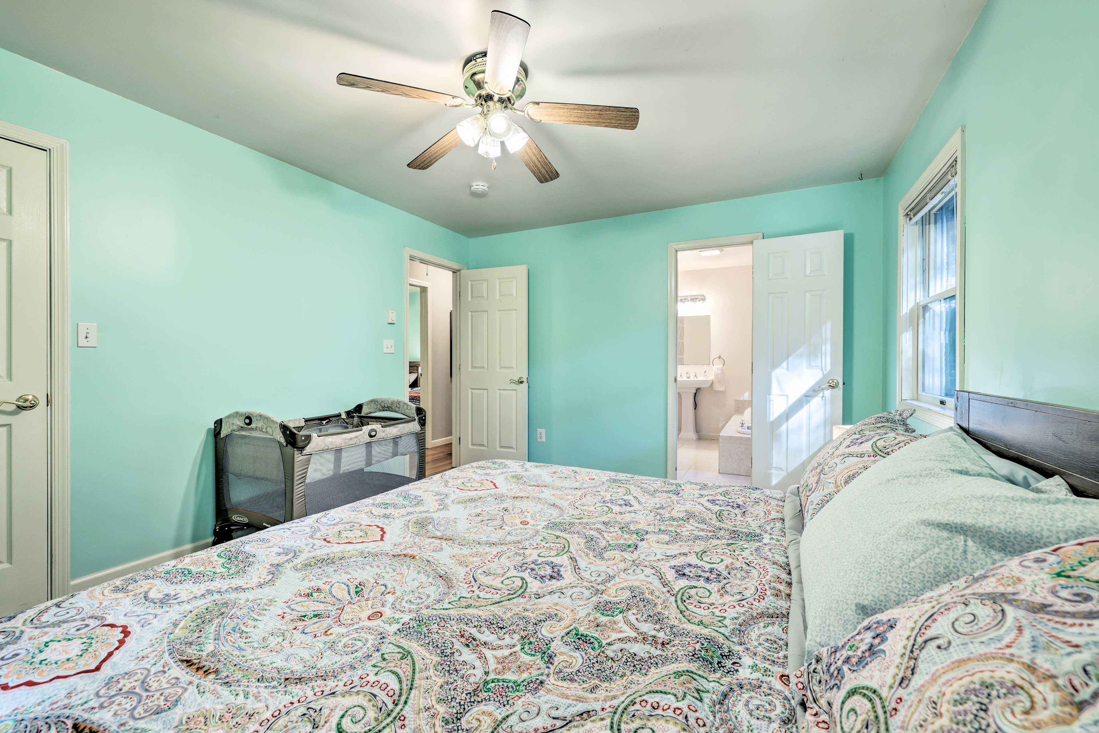 A bedroom with a bed, a ceiling fan, and a door leading to another room.
