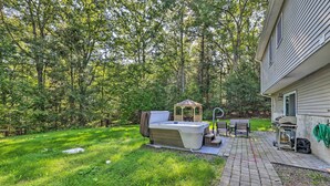 Un jardin avec un jacuzzi, un belvédère, une table de patio et un barbecue.