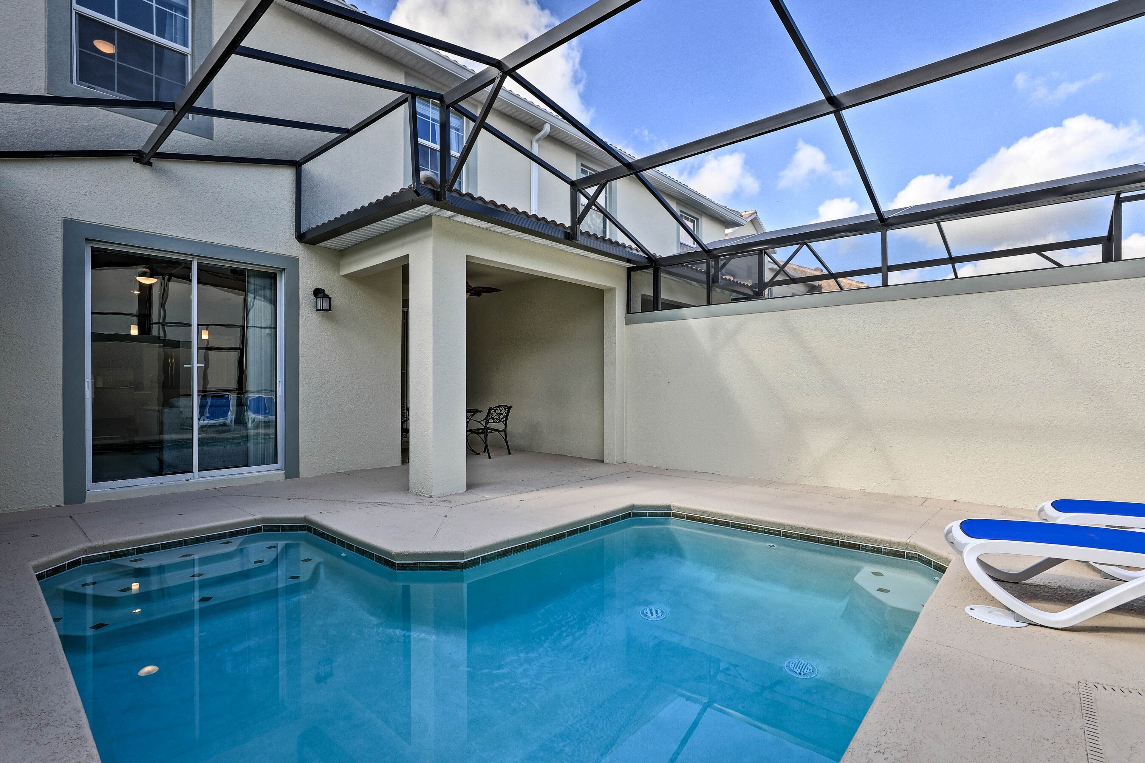 Ein Schwimmbecken mit Glasüberdachung, eine überdachte Terrasse und Blick zum Himmel.