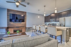 A modern kitchen with dark cabinets, a microwave, and a refrigerator. There is a dining area with a table and chairs.