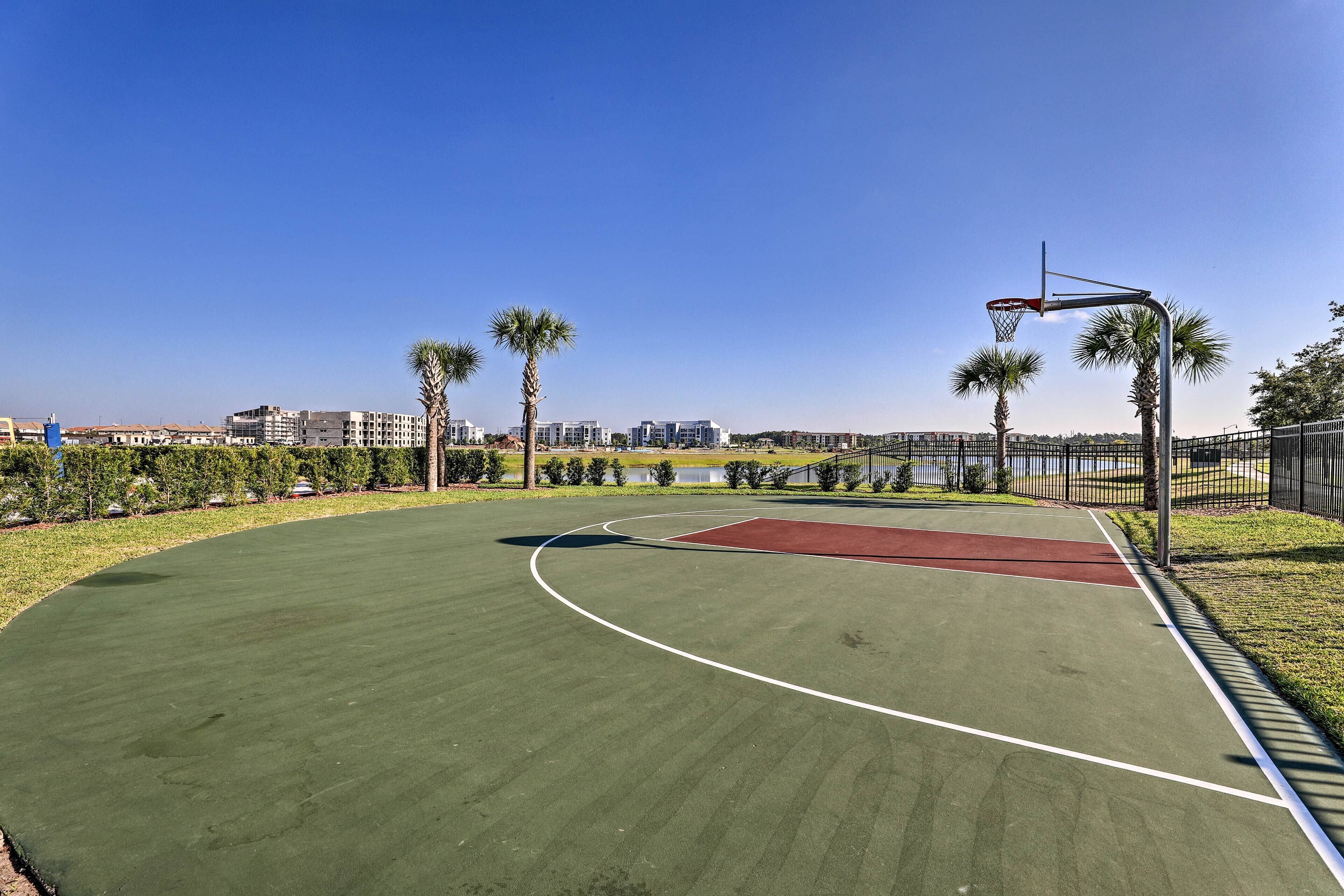 An outdoor basketball court with a clear view of the surrounding area, including buildings and palm trees.