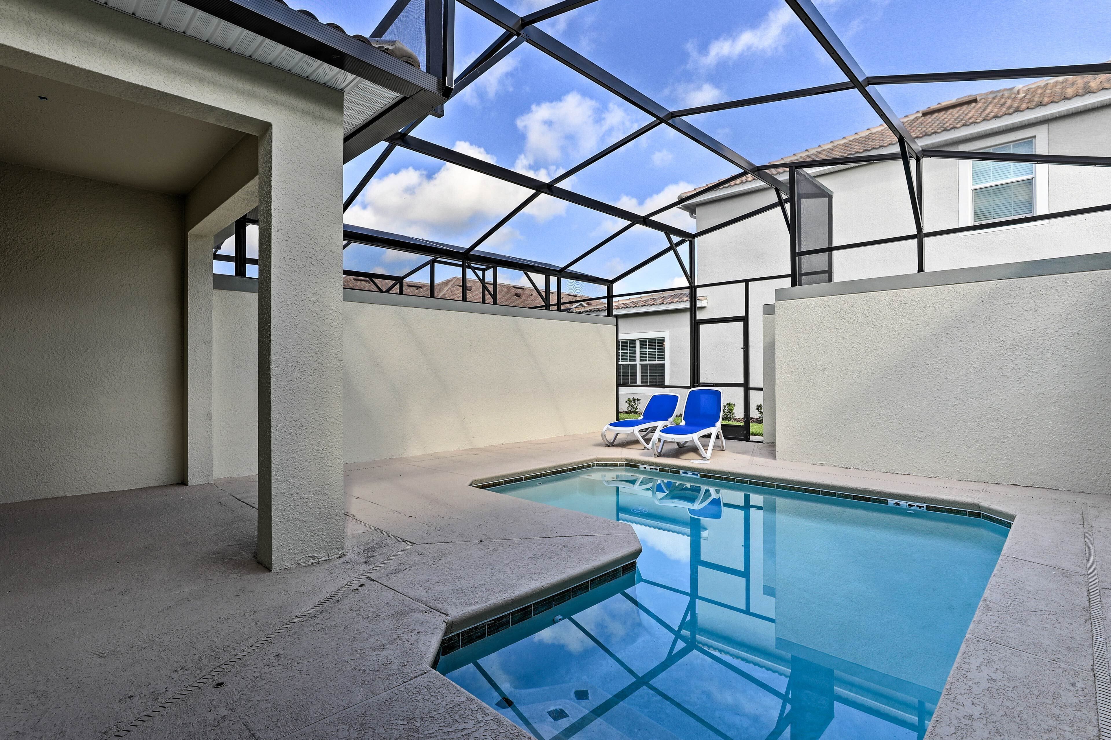 An indoor swimming pool with clear blue water, surrounded by a covered area with a metal frame roof.