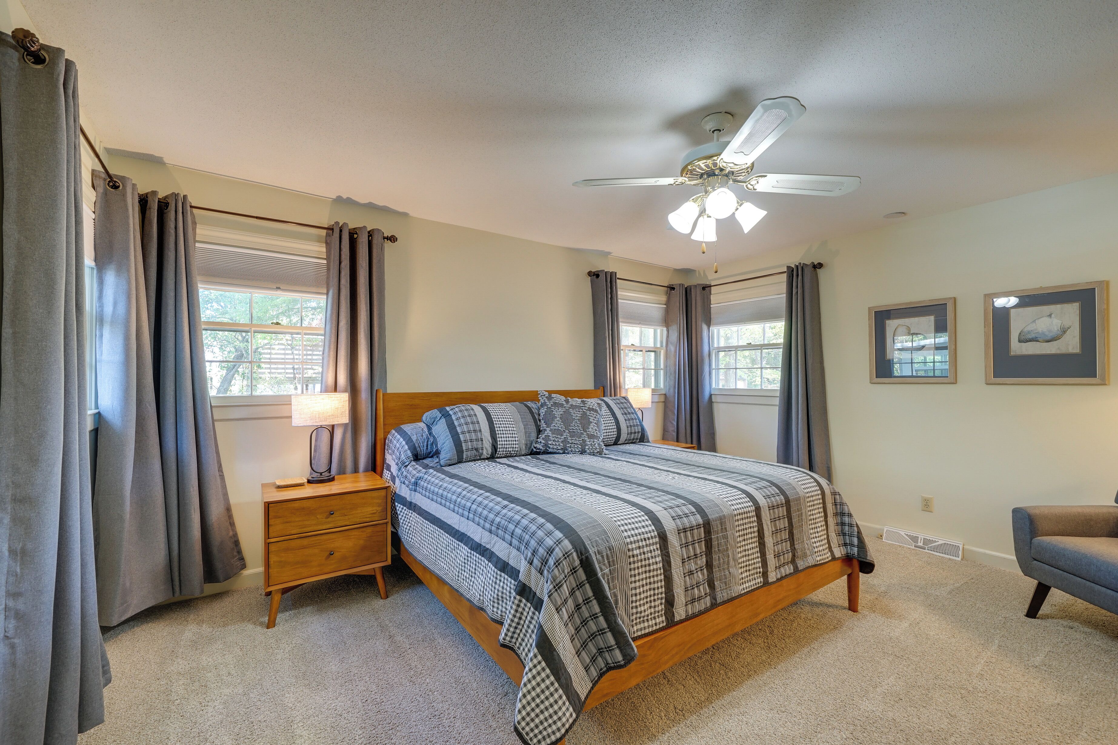 A bedroom with a bed, nightstands, a ceiling fan, and a chair.