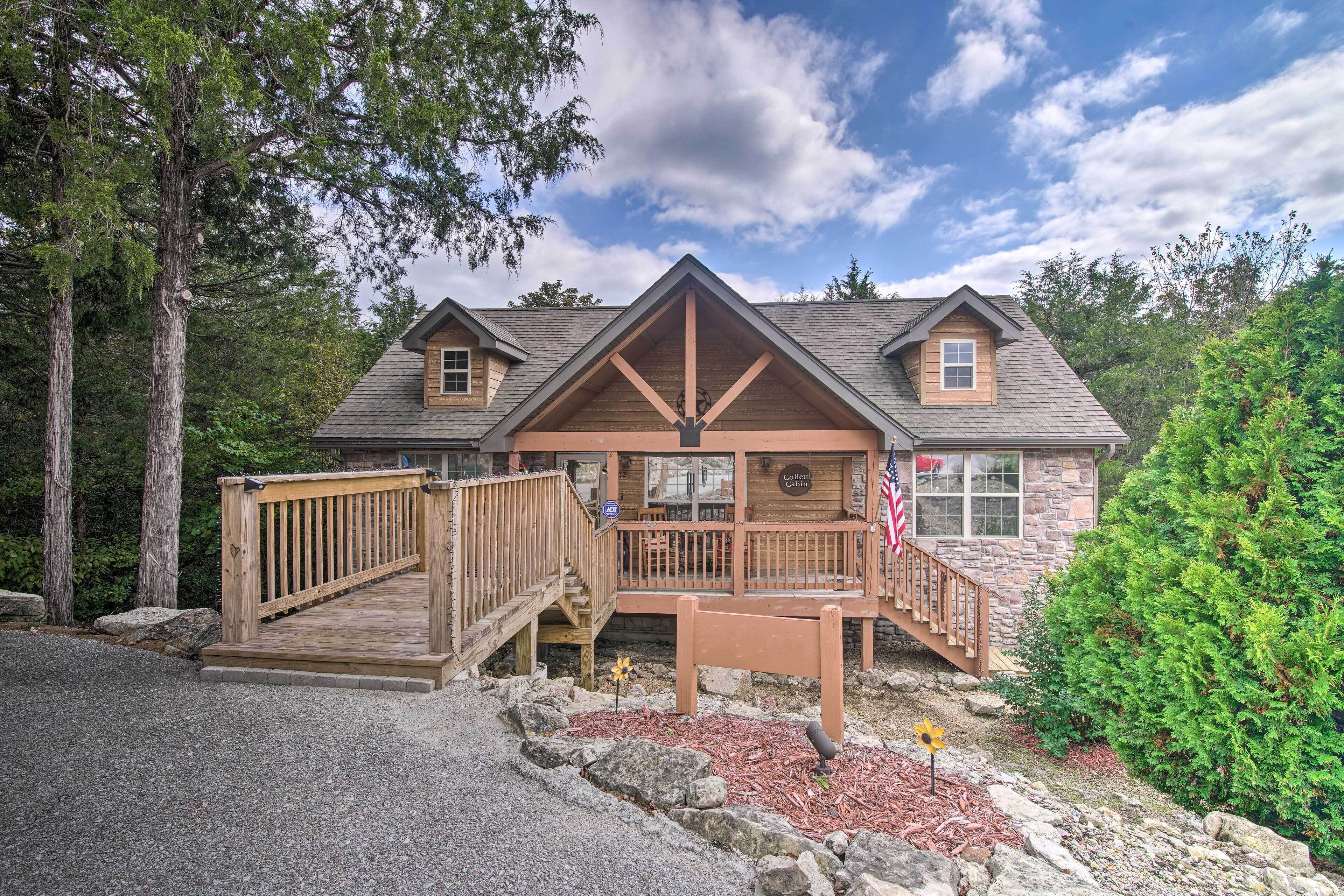 A lodge with a wooden deck, stone walls, and a flag. - Resort Perks! Woodsy Family Retreat Near SDC (Branson West)
