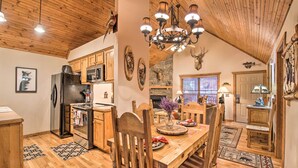 A spacious kitchen with wooden cabinets, a black refrigerator, and a dining area with a wooden table and chairs. - Resort Perks! Woodsy Family Retreat Near SDC (Branson West)