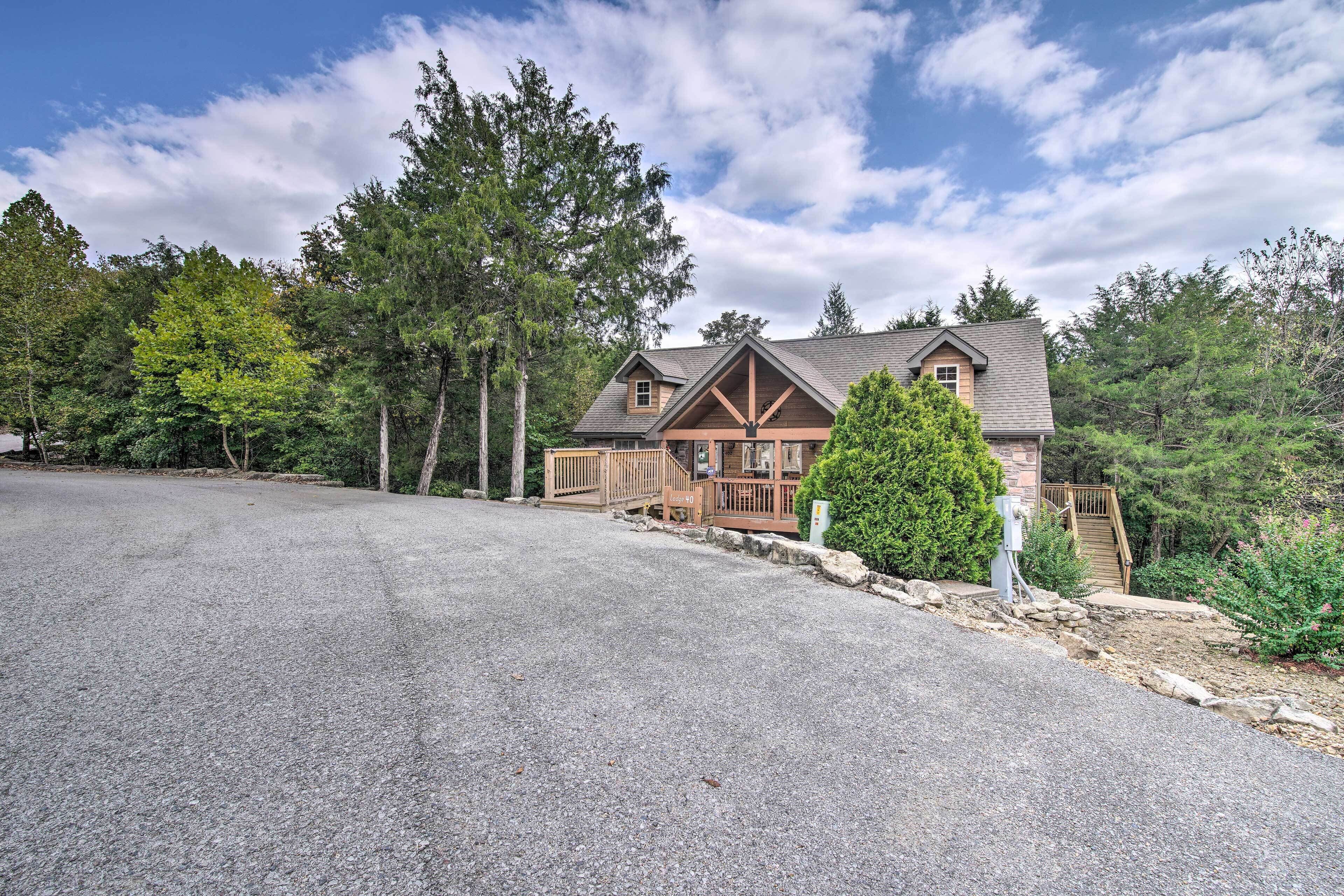 A two-story log cabin with a stone foundation, a wooden deck, and a covered porch.